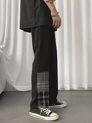 Men's black straight-leg chinos with plaid patchwork detail on the side.