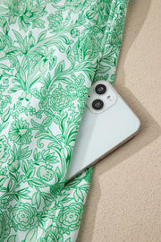Botanical print midi dress with pockets, showing a phone tucked into the side pocket.