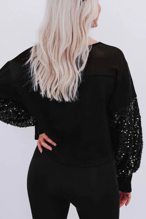 Black ribbed knit top with sequin sleeves and boat neckline.
