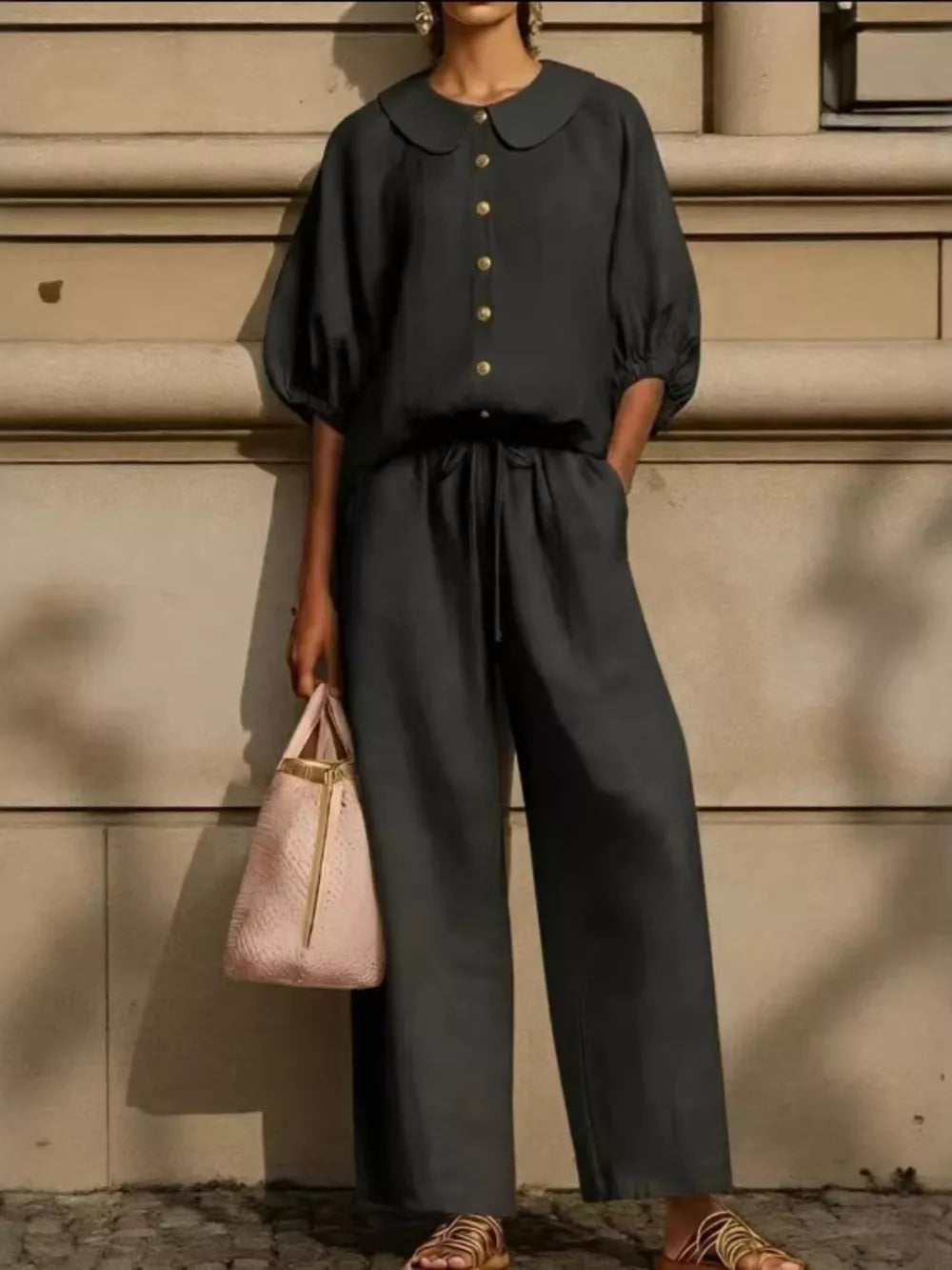 Black button-down two-piece set with drawstring pants and pocketed top, featuring a Peter Pan collar and puff sleeves.