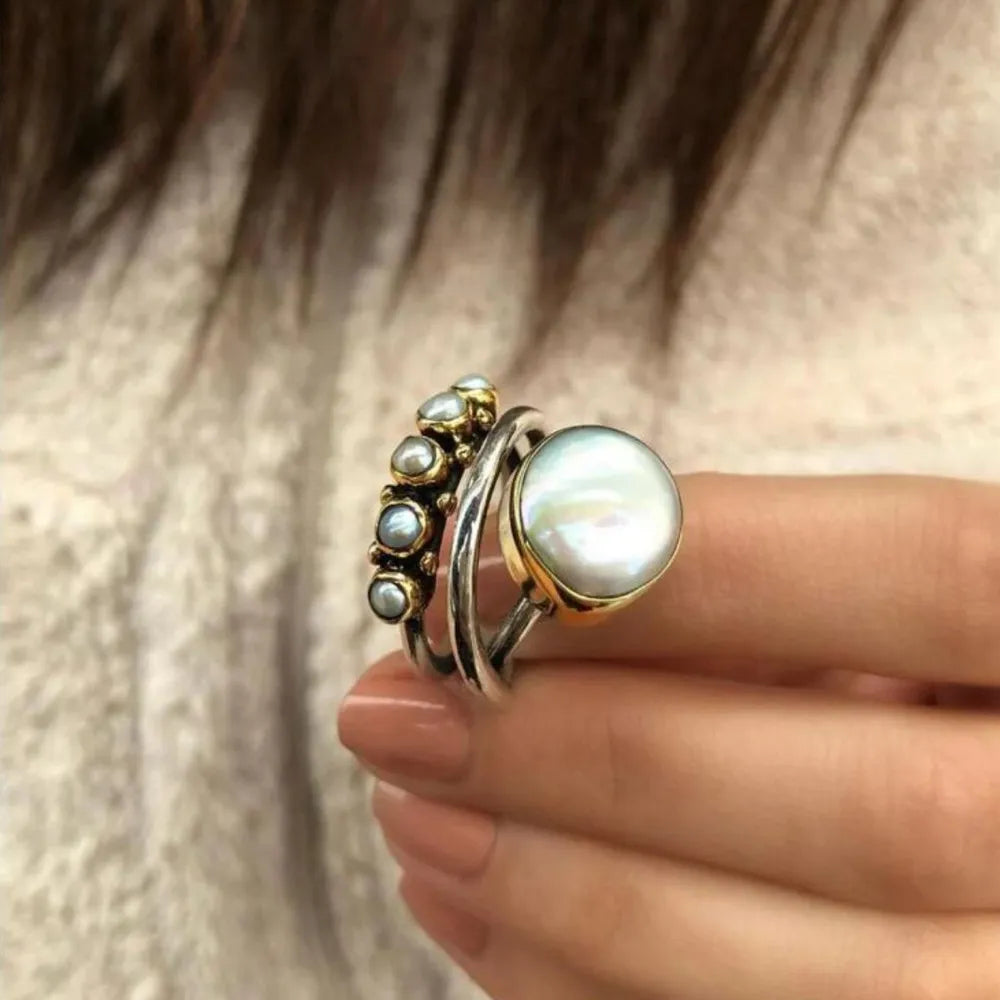 Pearl cluster trilogy ring with large central pearl and small side pearls on silver bands.