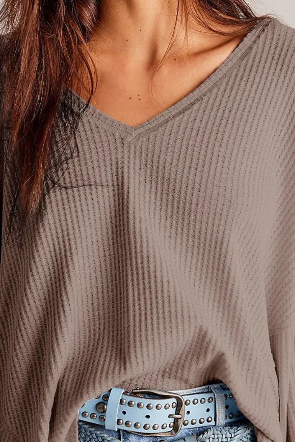 Waffle knit v-neck top in mocha with blouson sleeves, styled with a blue studded belt.