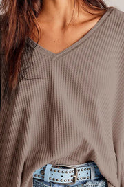 Waffle knit v-neck top in mocha with blouson sleeves, styled with a blue studded belt.