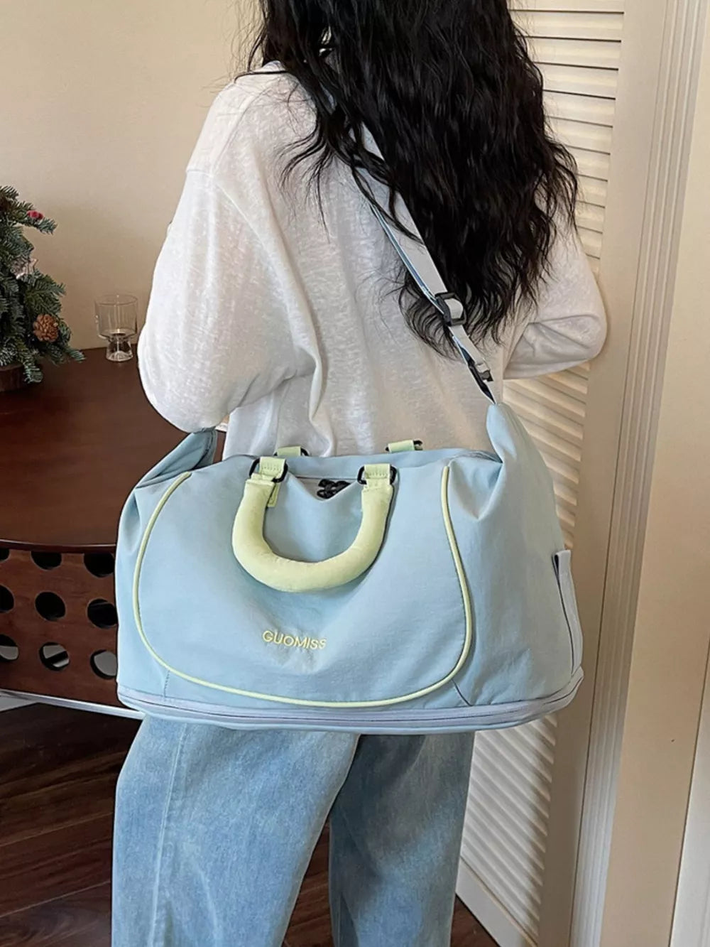Premium Oxford cloth duffle bag in blue with yellow trim and handles, worn by a woman.