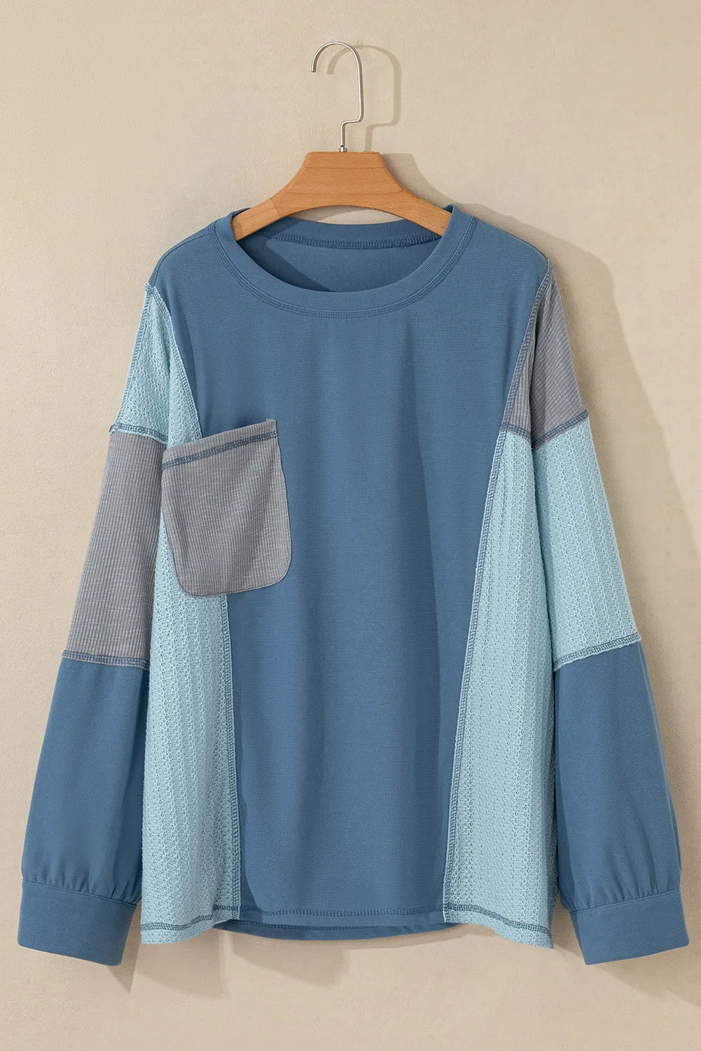 Panelled waffle knit blouson top in dusty blue with contrast grey pocket and sleeves.