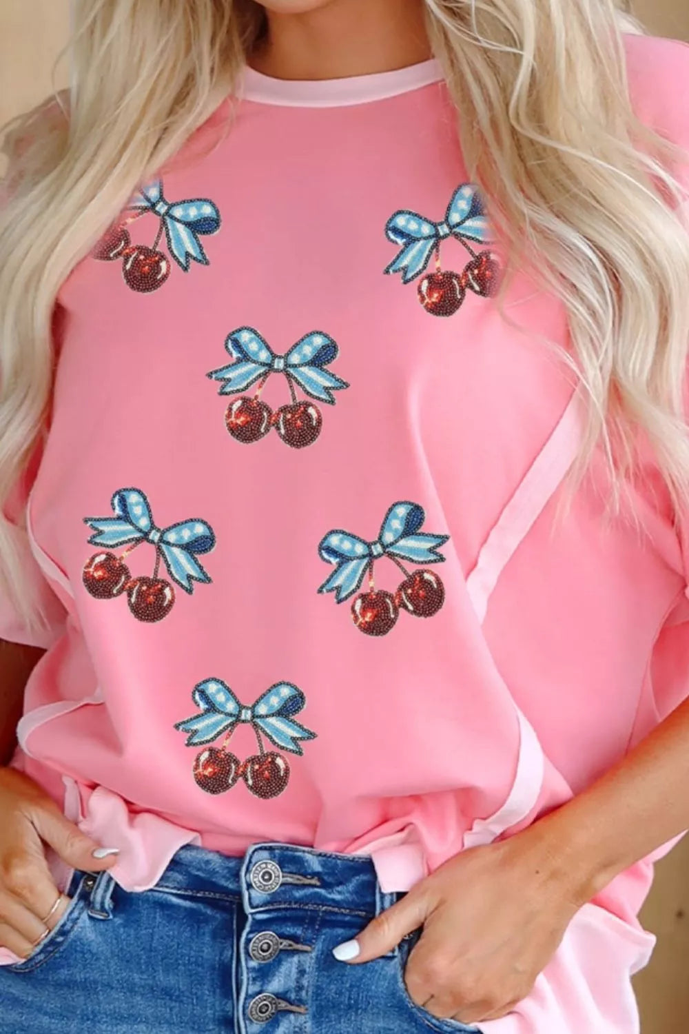 Pink polyester t-shirt with sequin cherry and bow graphic print.