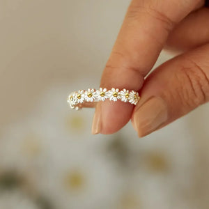Silver band ring with a continuous daisy chain pattern and yellow centers.