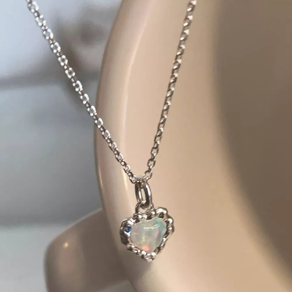 Charming heart pendant necklace in silver with opal and blue stone detail.