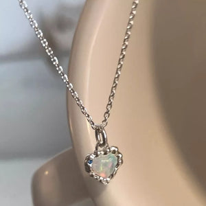 Charming heart pendant necklace in silver with opal and blue stone detail.