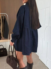 Dark blue denim mini dress with smocked cuffs and tiered skirt.