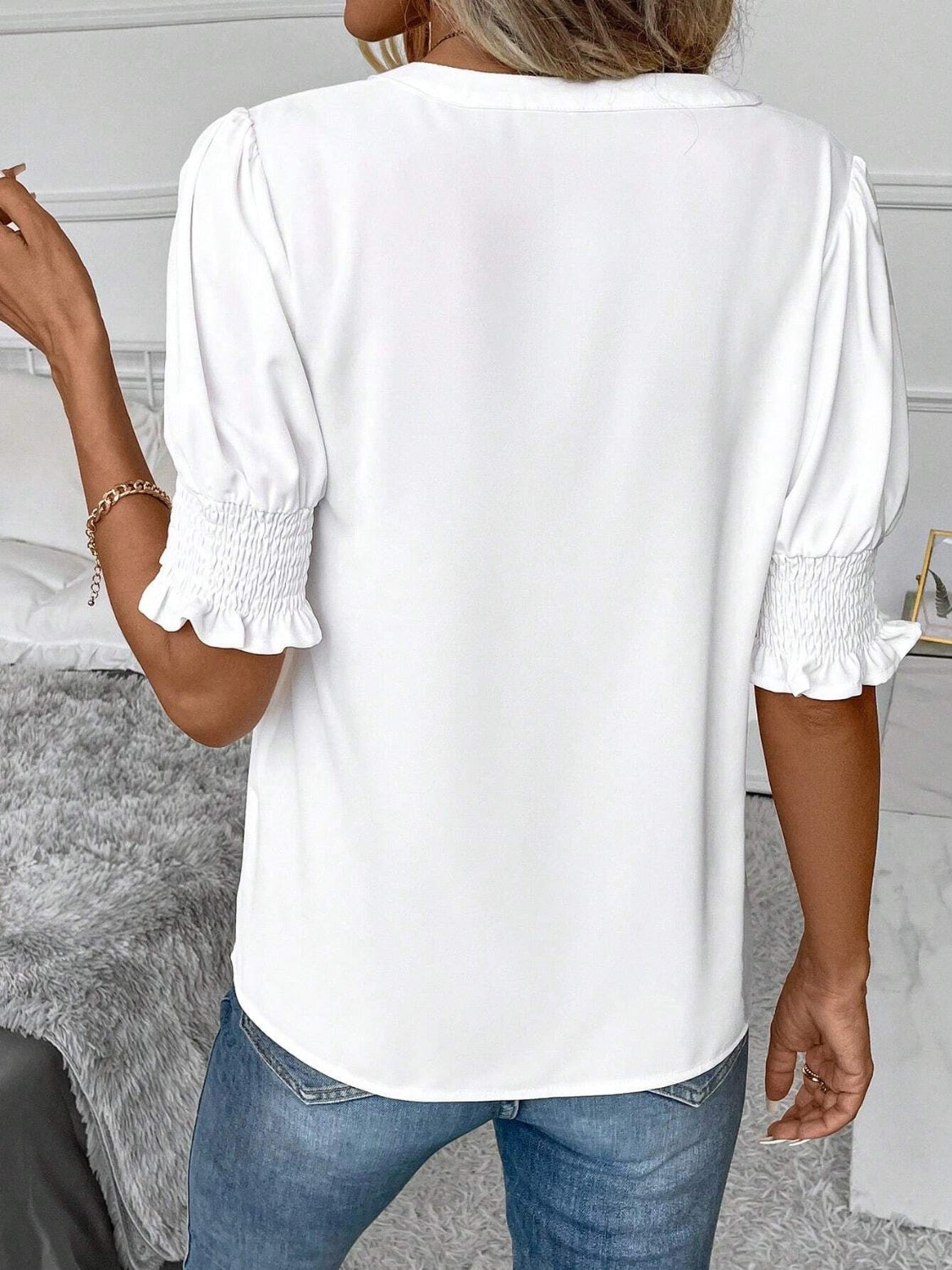 White shirred sleeve blouse with ruffle cuffs and a plunge neckline.