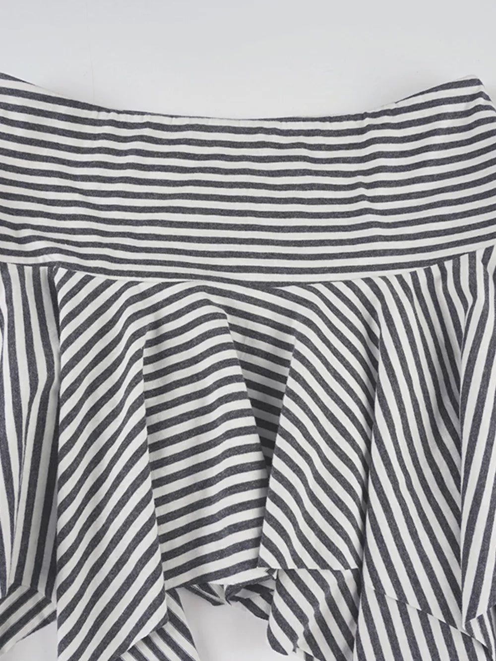 Asymmetrical hem mini skirt with black and white stripes and a ruffled detail.