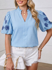 Embroidered puff sleeve blouse in light blue with a textured fabric and V-neck.