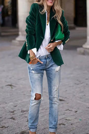 Emerald velvet blazer with gold buttons, worn casually with ripped jeans.