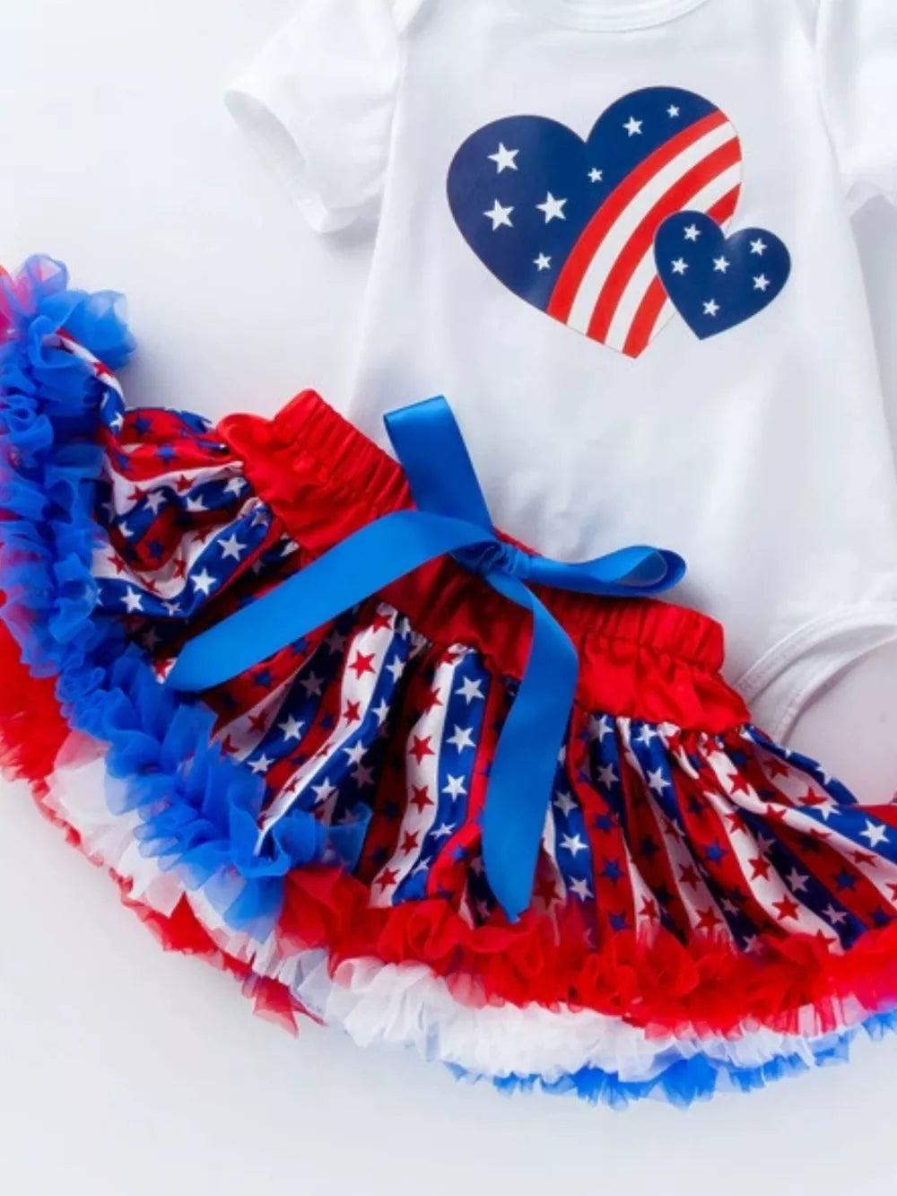 Baby girl 4-piece set with patriotic heart print bodysuit and ruffled star print tutu with blue bow.