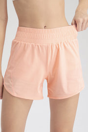 Layered performance running shorts in watermelon pink with elastic waistband and curved hem.