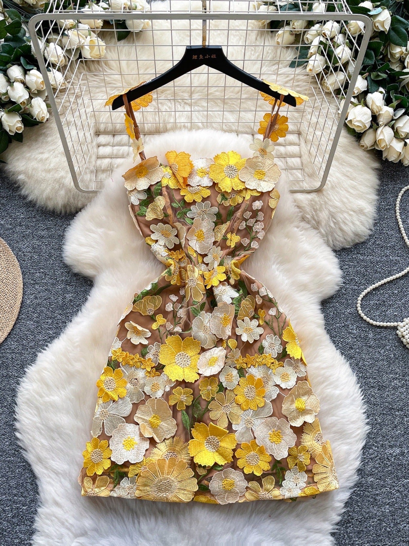 Embroidered floral mini dress with yellow and white flowers on a tan mesh.