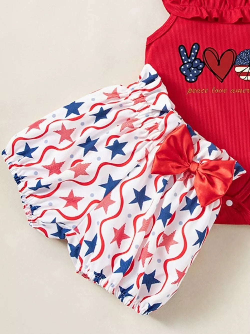 Red baby bodysuit with patriotic graphic and star print bloomer shorts with bow.