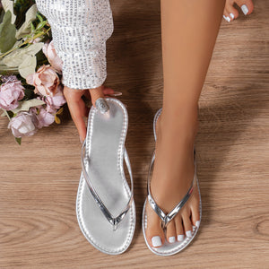 Silver minimalist toe-post sandals with a sleek metallic finish and a decorative ring detail.