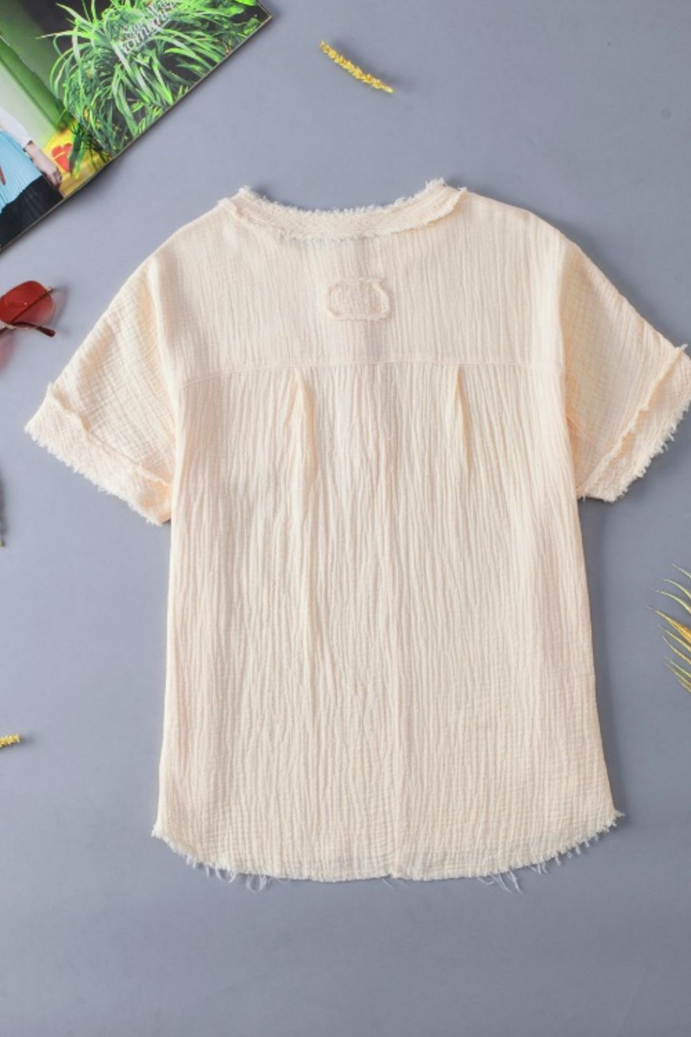 Beige textured gauze henley blouse with raw edges and button detail.