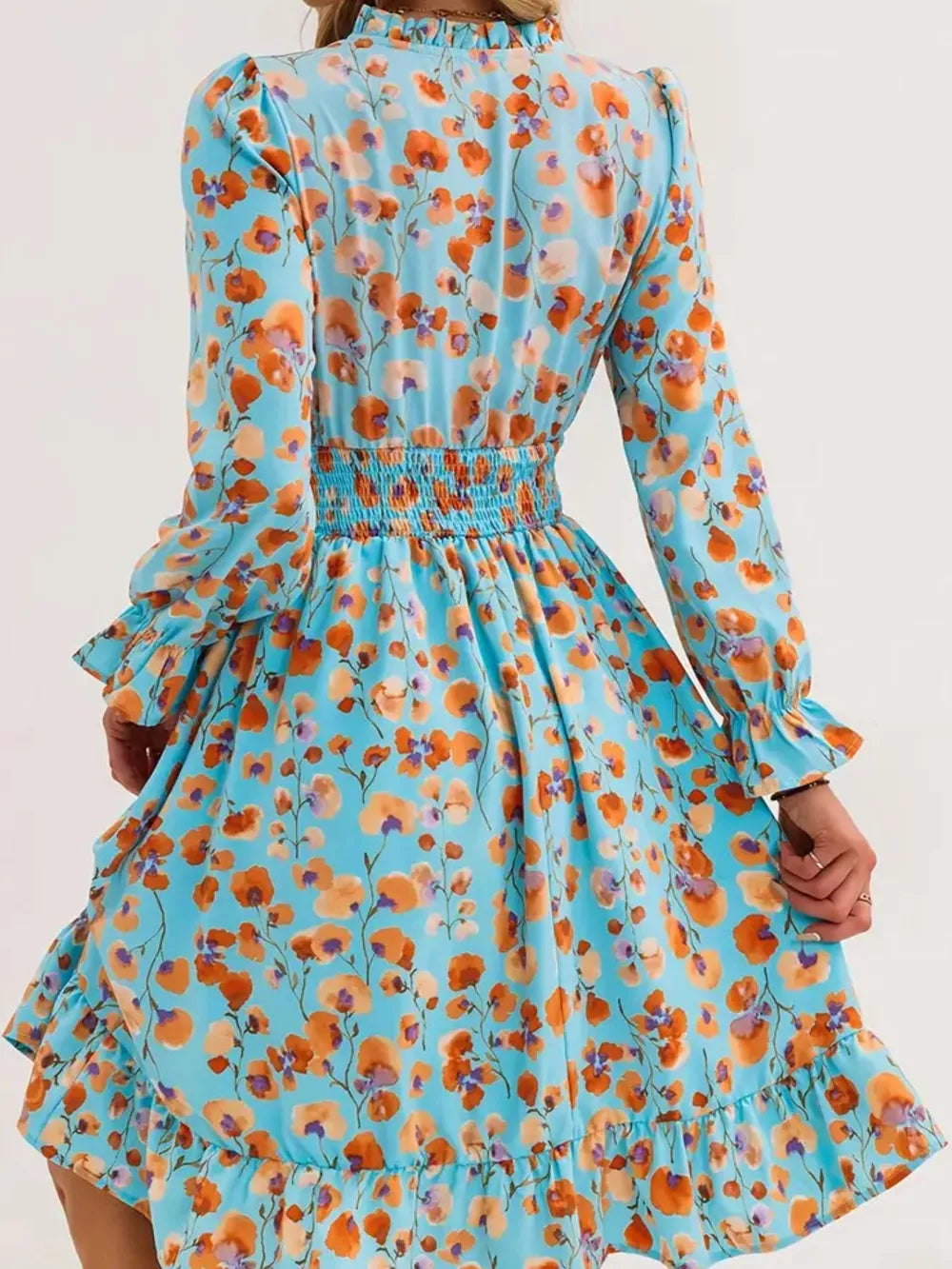 Pastel blue floral dress with smocked waist, ruffle cuffs, and ruffled hem.