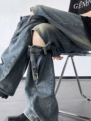Distressed blue wide-leg jeans with decorative straps and knee cutouts.