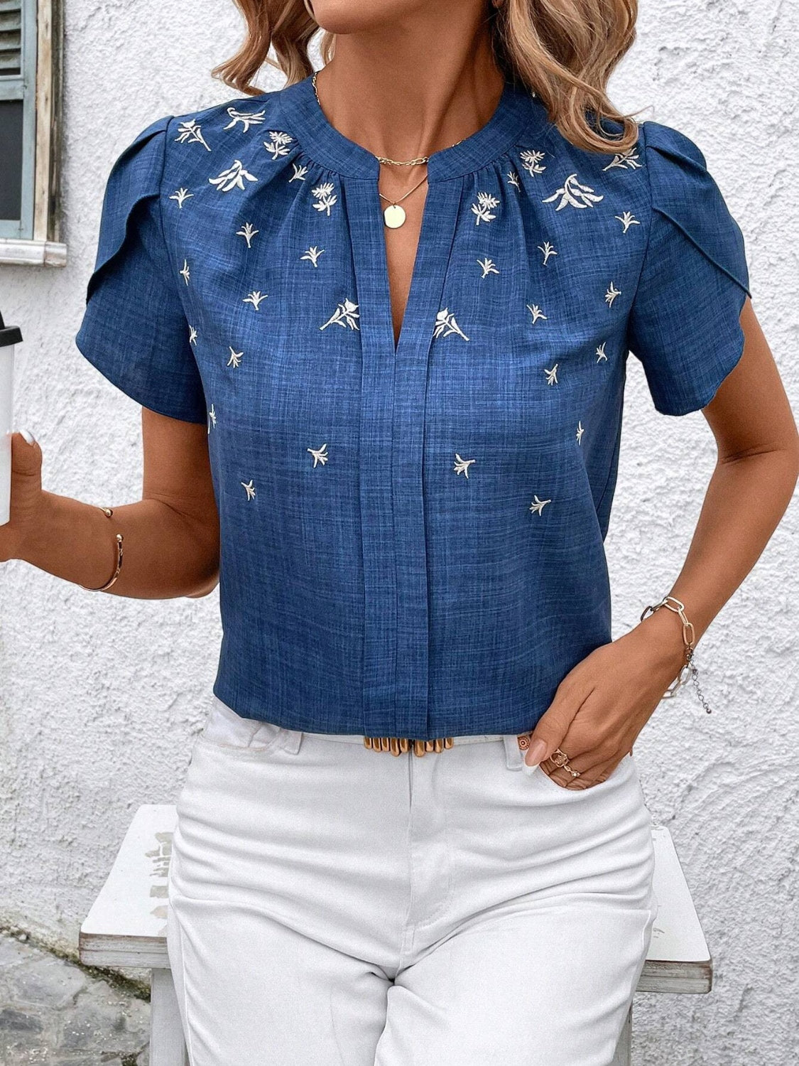 Blue embroidered floral keyhole blouse with short flutter sleeves and a split neckline.