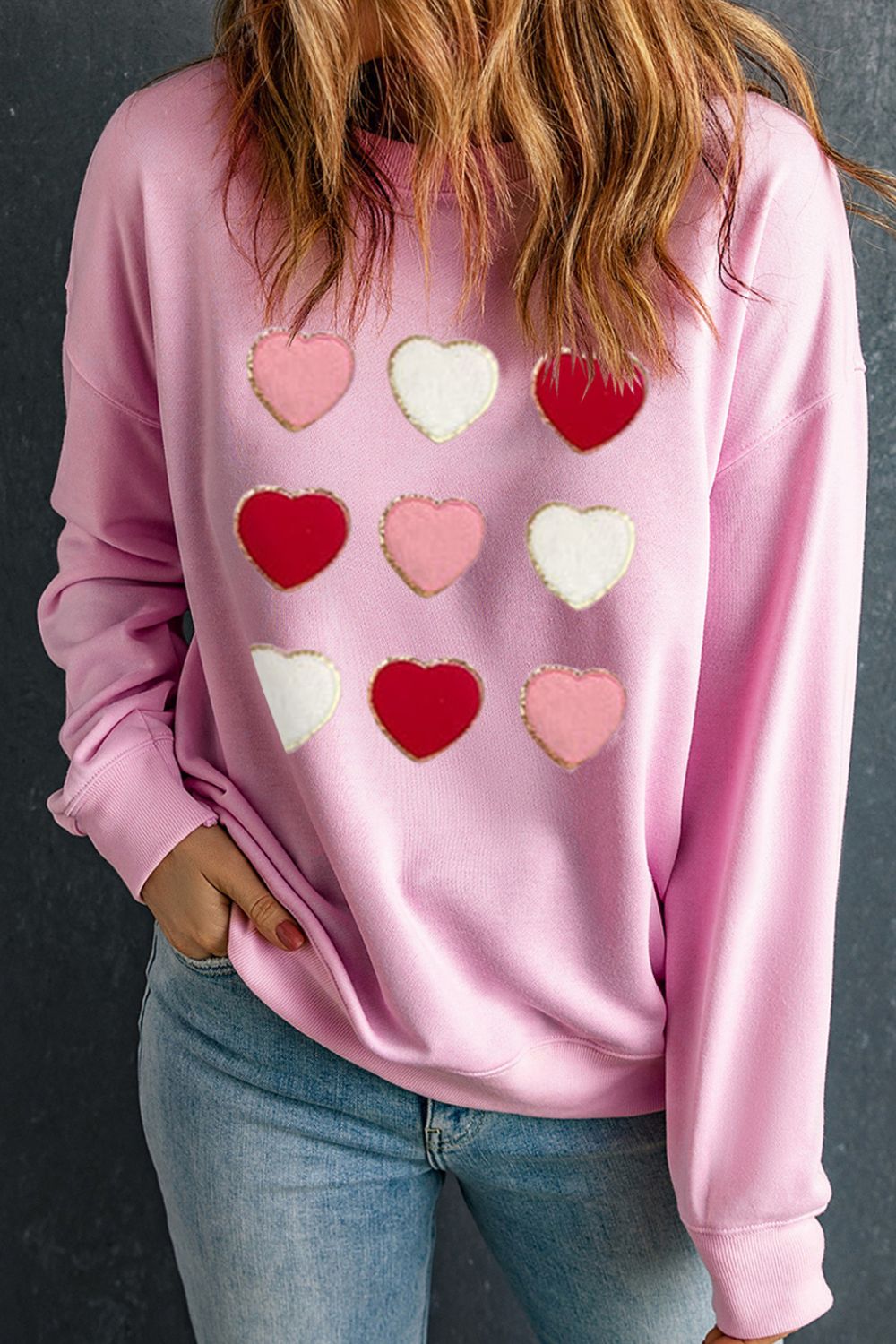 Blush pink sweatshirt with an allover embellished heart grid pattern.