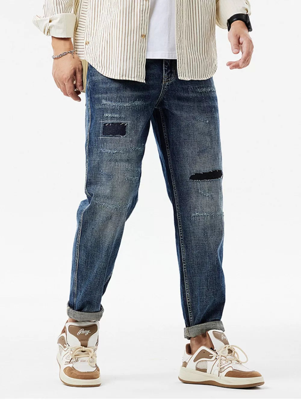 Men's dark blue distressed cotton jeans with patchwork details and cuffed hems.