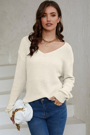 Relaxed knit V-neck pullover sweater in beige with long sleeves and a textured stitch.
