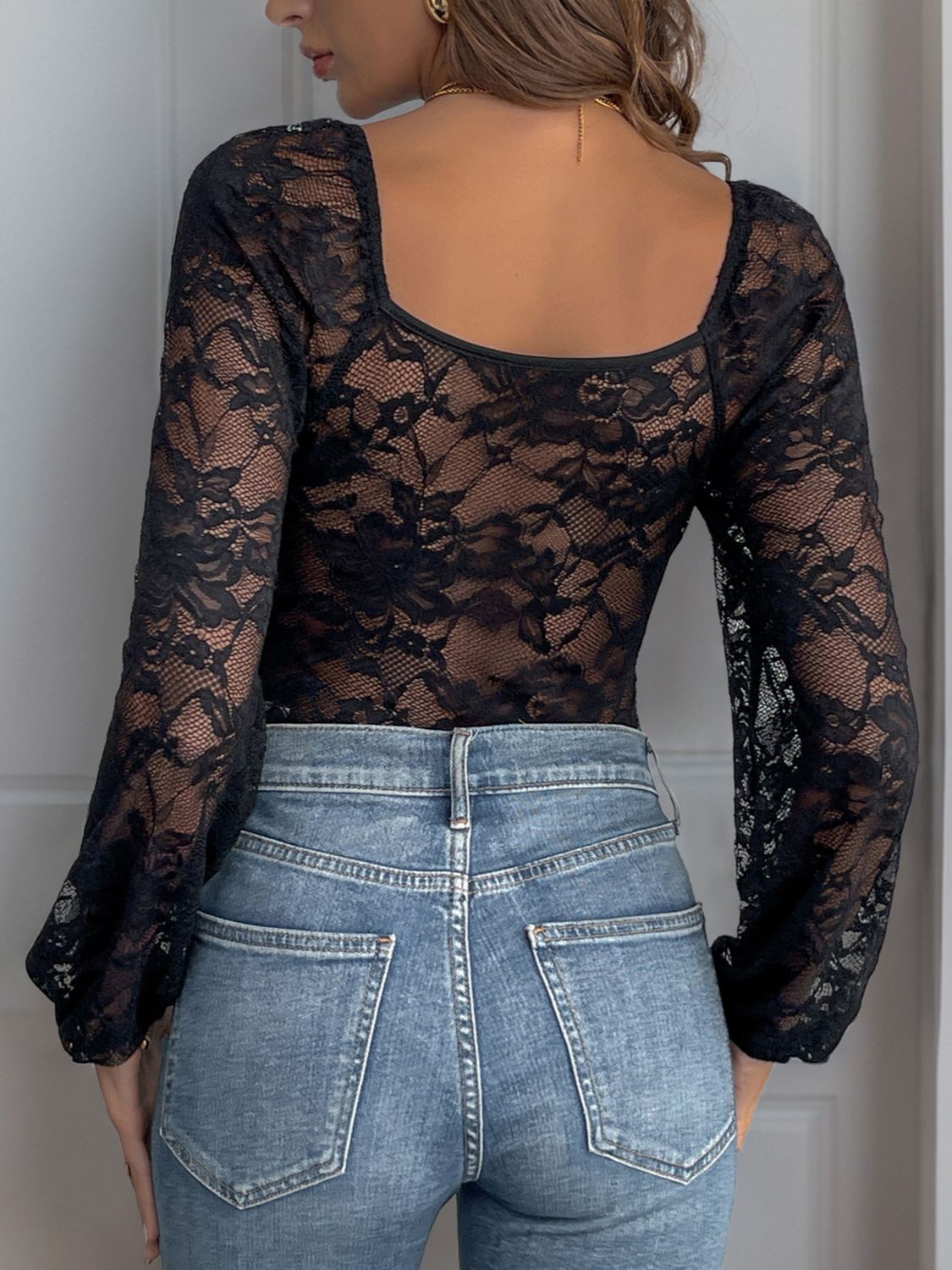 Black lace bodysuit with blouson sleeves and square neckline, paired with denim jeans.