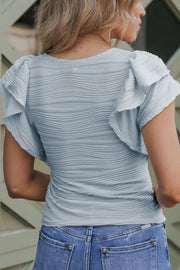 Light blue textured bodysuit with ruffle sleeves and a ruched bodice.