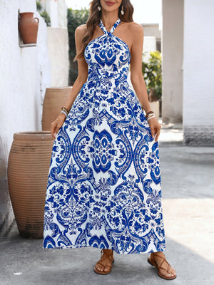 Blue and white patterned maxi dress with crisscross halter neckline and flowing skirt.