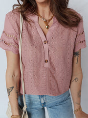 Pink eyelet embroidered short-sleeve blouse with button-down neckline and cut-out details.