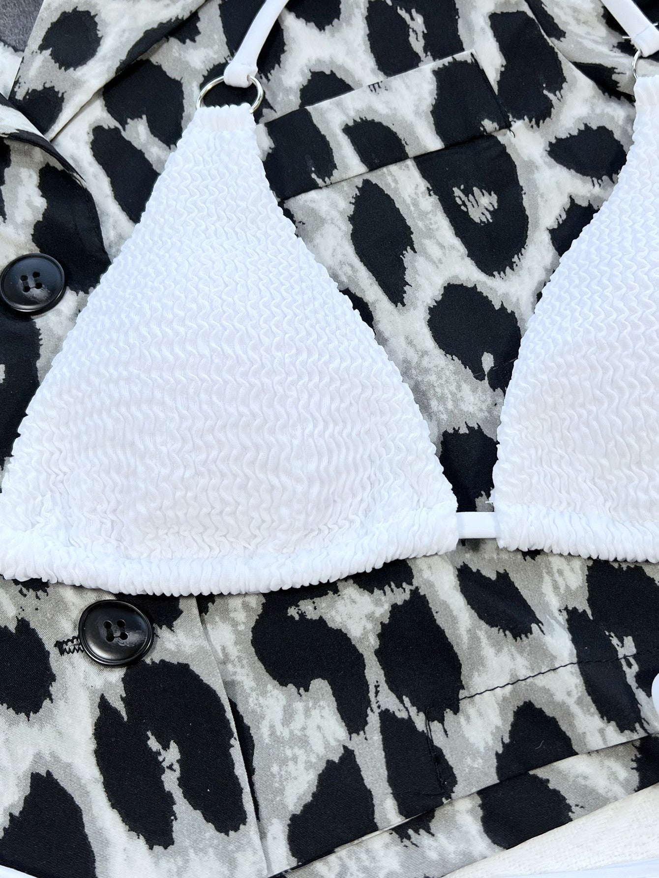White textured bikini top with ring detail, shown with leopard print jacket.