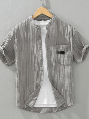 Grey textured button-up shirt with mandarin collar and chest pocket, short sleeves.