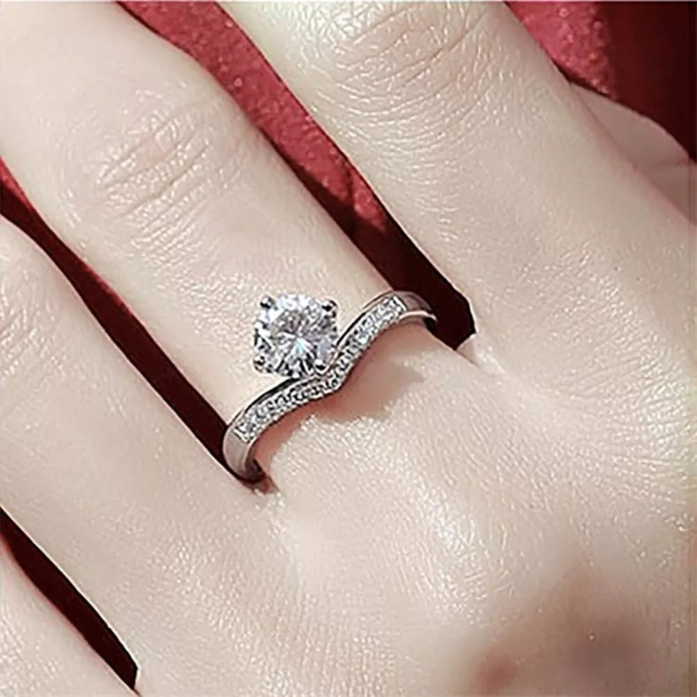 Sterling silver ring with a large center moissanite and small accent stones on a V-shaped band.