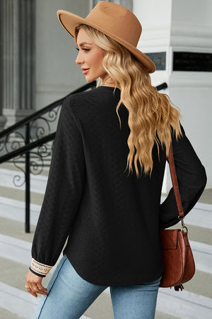 Black textured V-neck blouse with lace trim cuffs and long sleeves.