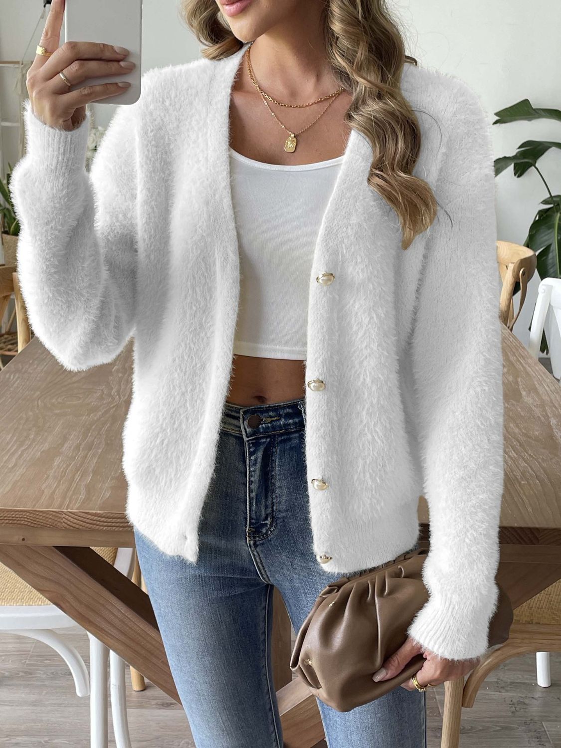 White plush button-down cardigan with pearl details and long sleeves.
