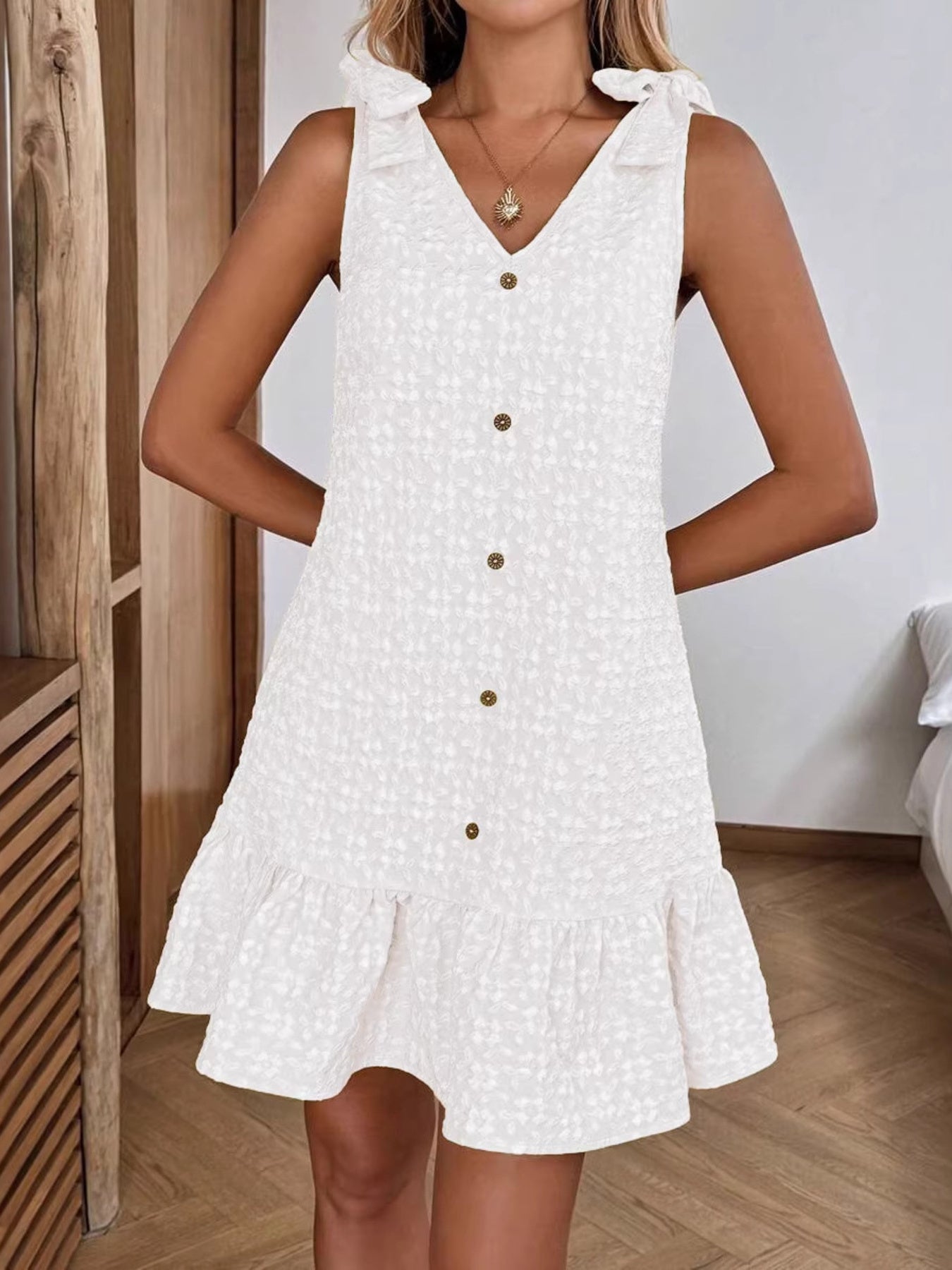 White button-front V-neck ruffled dress with tie shoulders and textured fabric.
