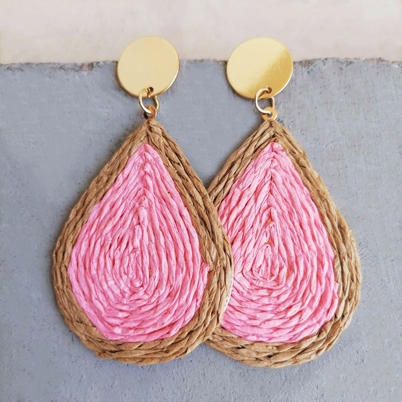 Pink raffia teardrop statement earrings with woven natural raffia trim and gold disc tops.