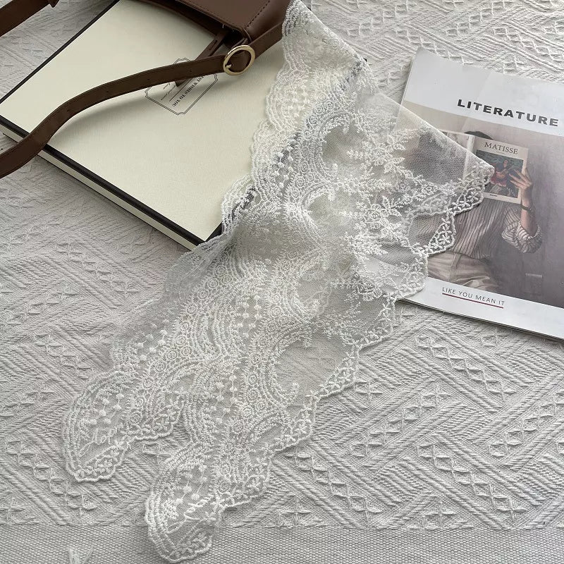 Delicate floral lace scarf in off-white with intricate patterns and scalloped edges.