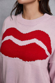Blush pink knit sweater with a large red kiss graphic and distressed hem.