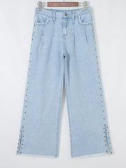 Light wash denim wide-leg jeans with studded side slits and frayed hem.