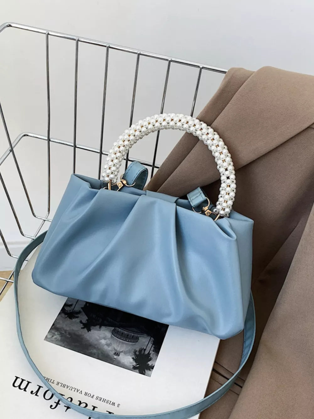 Blue crossbody bag with pearl-beaded handle and ruched detail