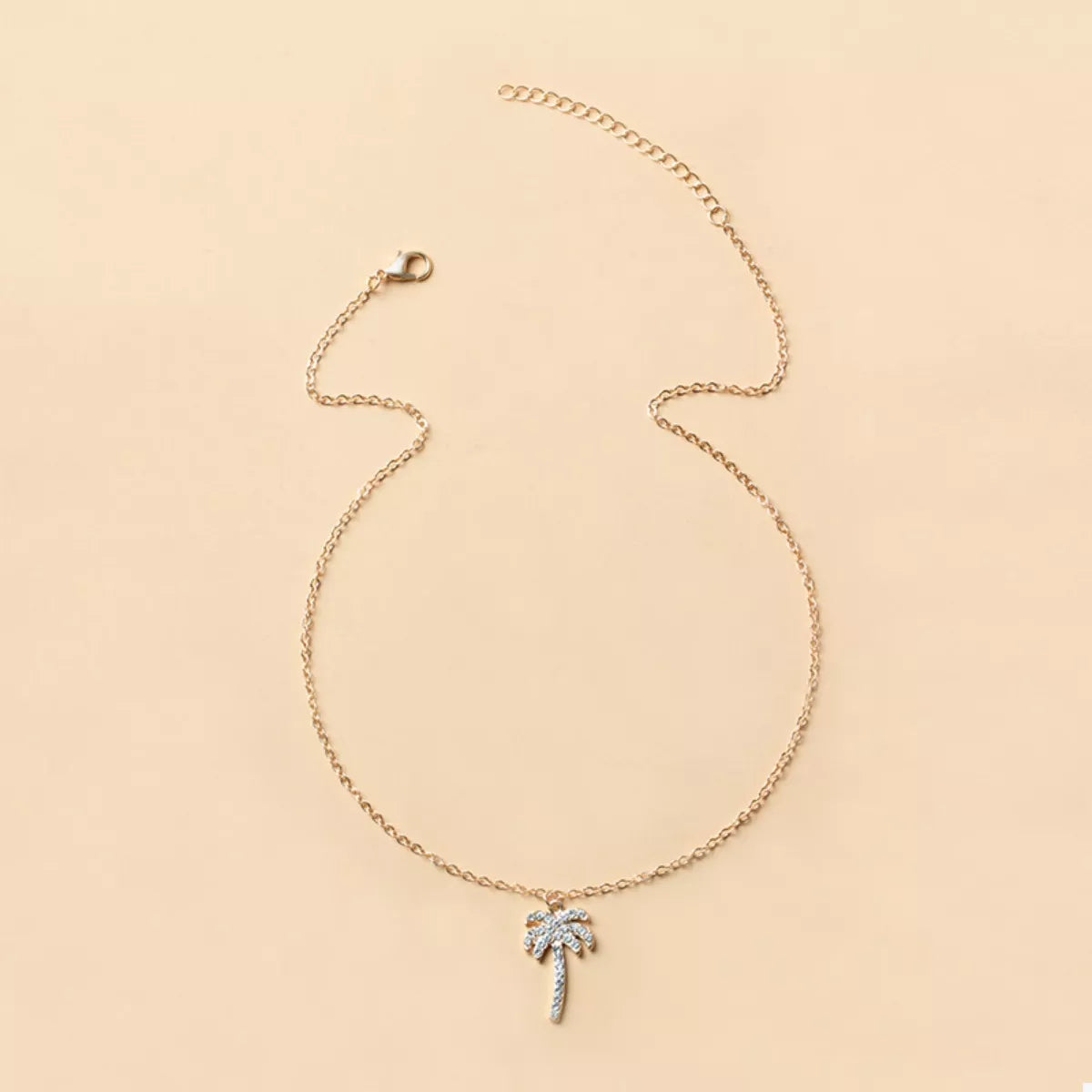 Gold palm tree pendant necklace with sparkling details on a delicate chain.