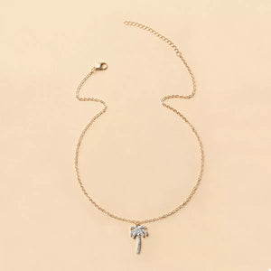 Gold palm tree pendant necklace with sparkling details on a delicate chain.