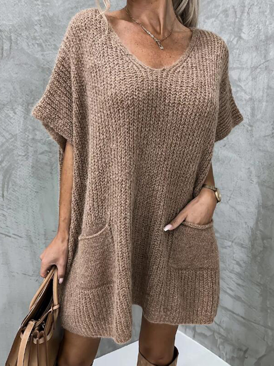 Taupe knit tunic with V-neck, short sleeves, and two front pockets.