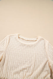 Beige textured blouse with crew neck and ruffle hemline detail