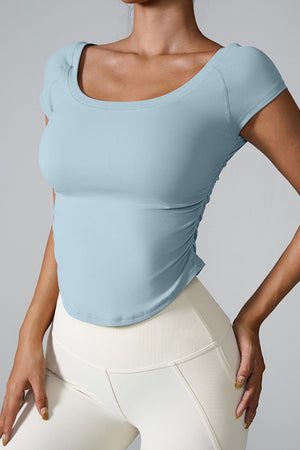 Light blue performance tee with gathered side detail and scoop neck.